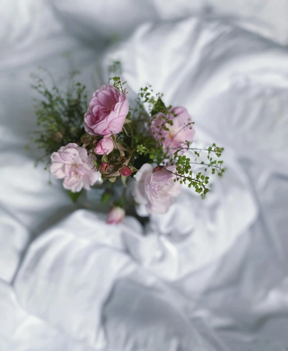 a bouquet of flowers is on top of a white bed sheet