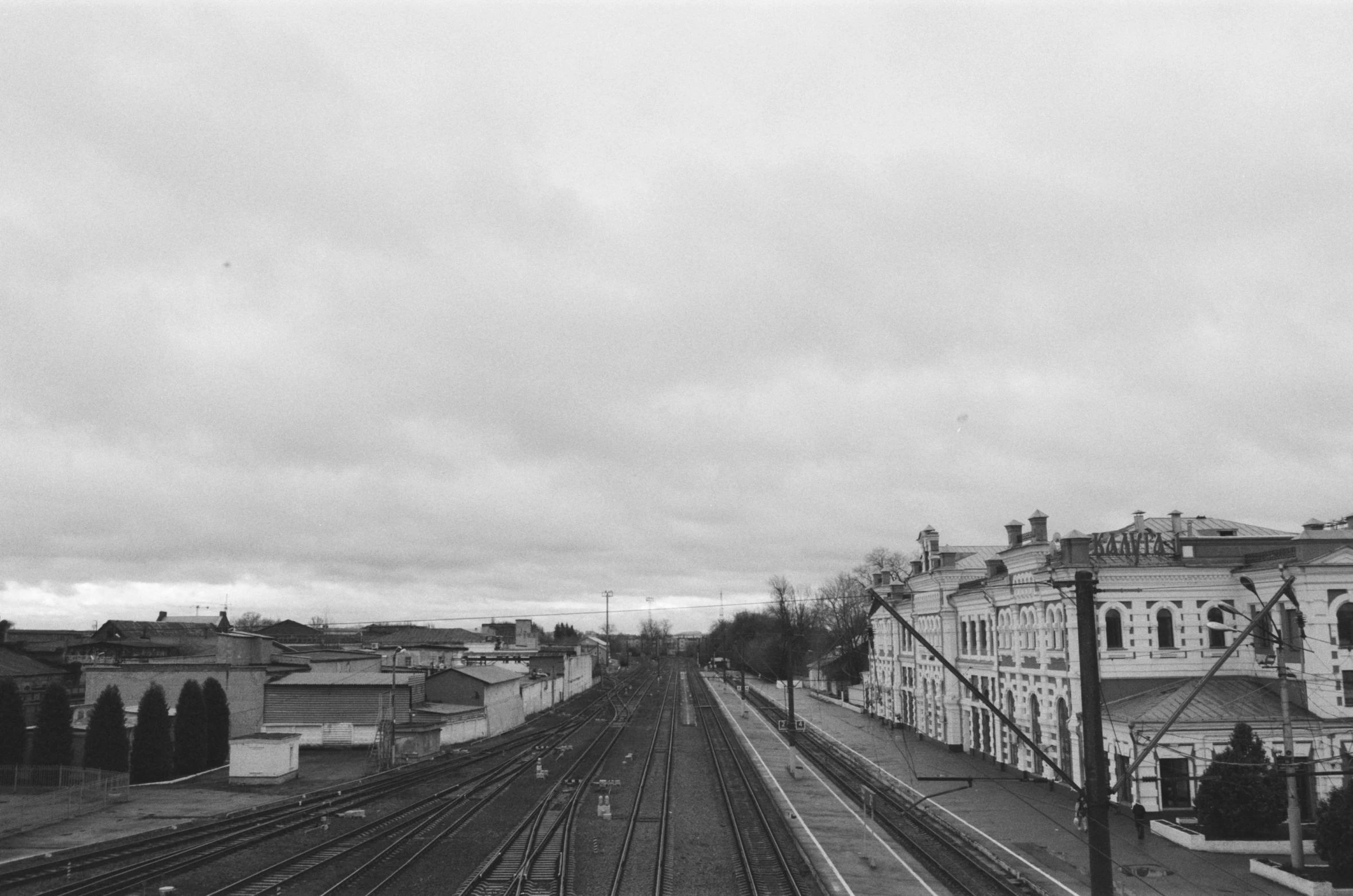 a black and white photo of a train track, white houses, cloudy day, abdulov, on a cloudy day