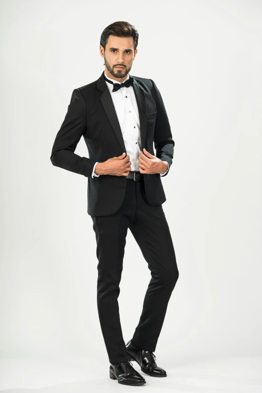the man in a tuxedo is standing in front of a white background