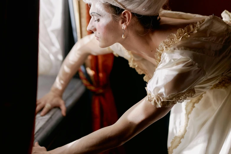 an older woman in a dress standing next to a window