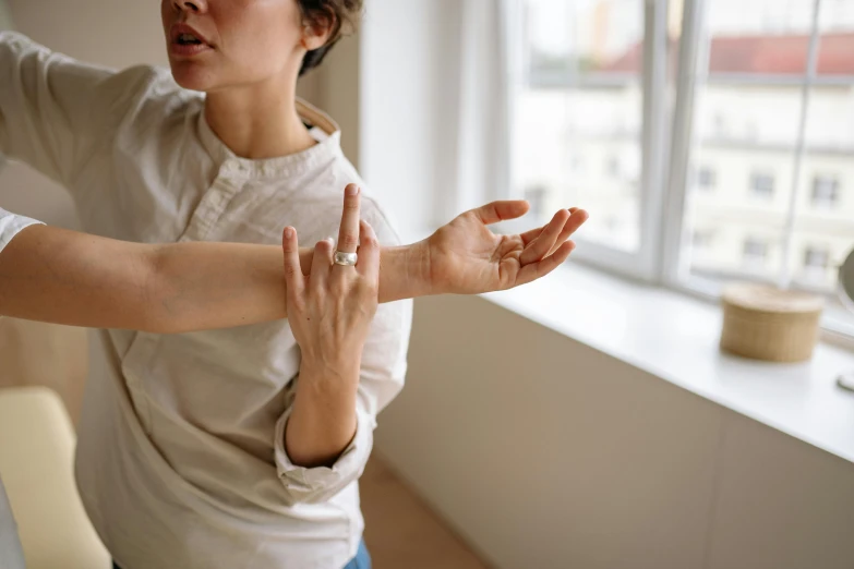 a woman that is standing in front of a window, by Nina Hamnett, trending on pexels, kinetic art, laying down with wrists together, tai chi, cysts, hands on counter