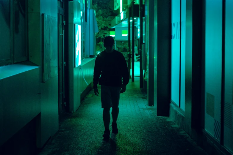 a person walking down a long hallway in a building, inspired by Liam Wong, dark teal lighting, standing in a township street, green neon, cinestill colour