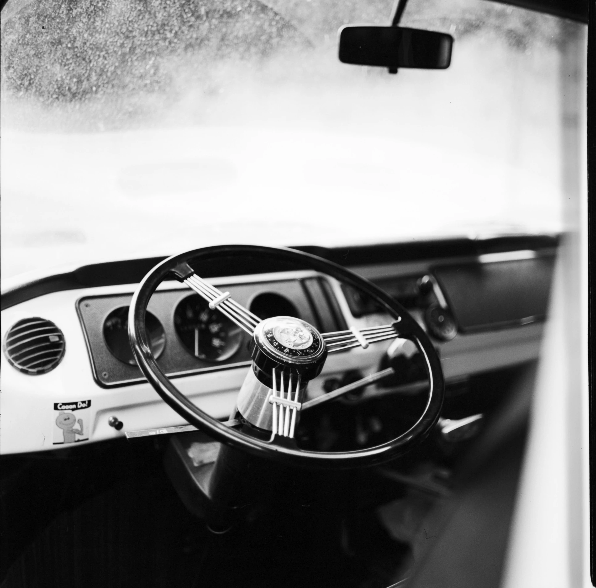 a black and white photo of a car dashboard, a portrait, by Mike Bierek, ffffound, inside on a rainy day, archival pigment print, single steering wheel