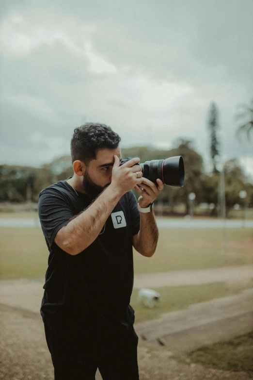 a man taking a picture with a camera, on a soccer field, dan dos santos, professional photo-n 3, profile