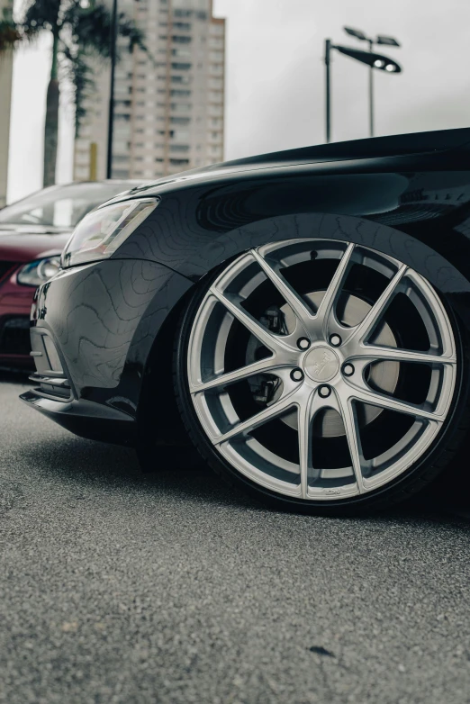 two parked cars in parking lot with tall buildings