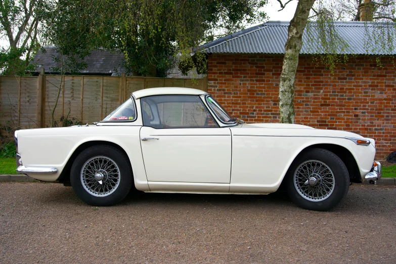 an old classic sports car sits parked on the side of a road