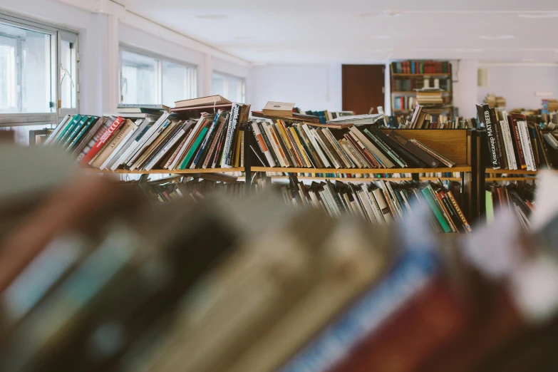 a bookshelf filled with lots of books in a library, pexels contest winner, vinyl material, thumbnail, stack of books on side table, distant photo