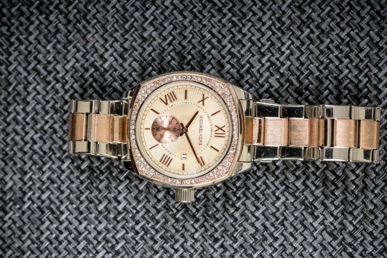 a close up of a watch on a table, a portrait, inspired by Porfirio DiDonna, unsplash, michael kors, katherine mcnamara inspired, two - tone, golden armor with diamonds