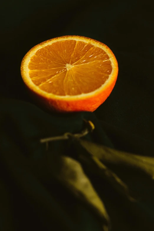 an orange sitting on top of a black surface, a still life, pexels, still life photo of a backdrop, half turned around, organics, adult