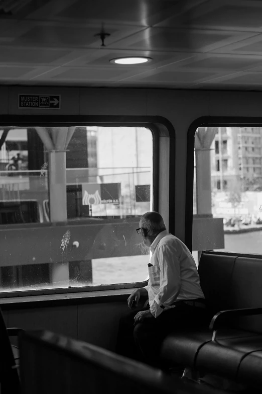 a man sitting on a train looking out the window, a black and white photo, inspired by Louis Stettner, postminimalism, interior of staten island ferry, ((portrait)), on a boat, 8k 50mm iso 10