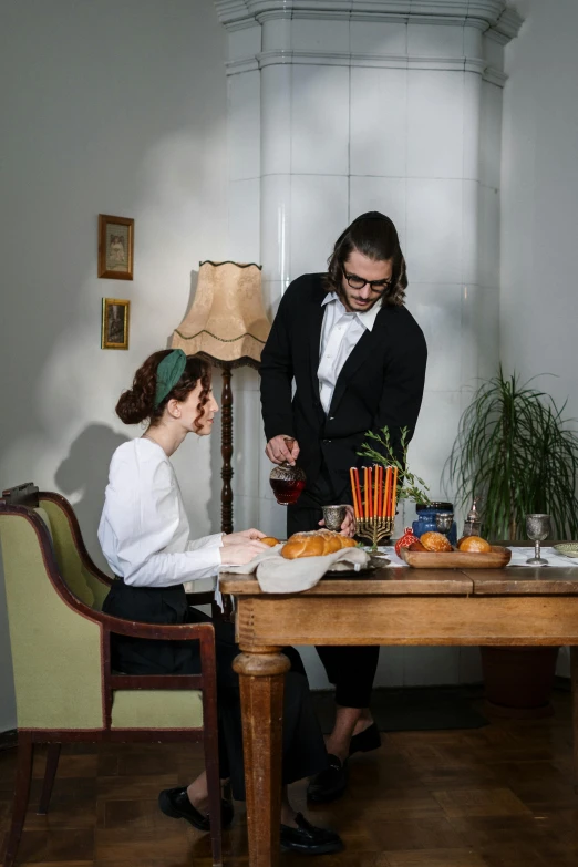 a lady sitting at a dining table as another stands over her