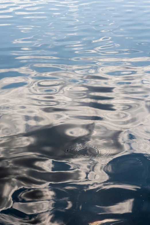 a close up of a body of water with clouds in the sky, by Jan Rustem, swirly liquid ripples, dappled sunlight, clear reflection, close - up photograph