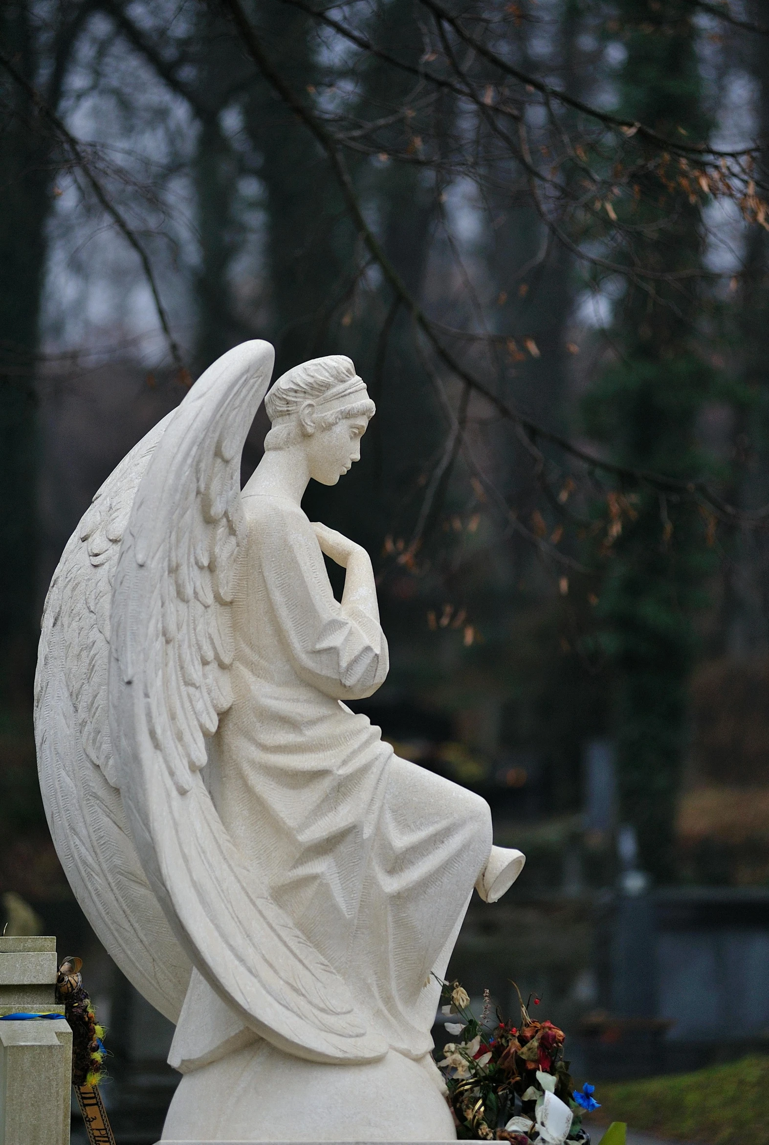 a statue of an angel sitting on a grave, looking off into the distance, large white wings, paul barson, cementary