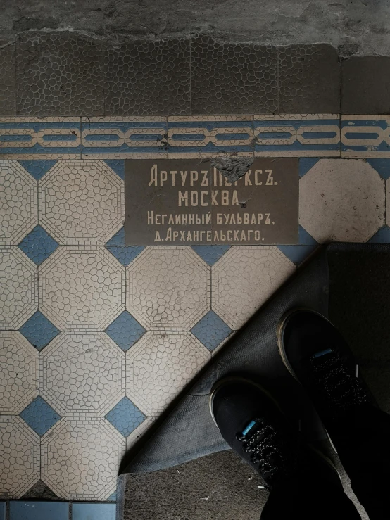 a person standing in front of a tiled wall, an album cover, inspired by Fyodor Alekseyev, carved floor, sneaker photo, moscow, 🚿🗝📝