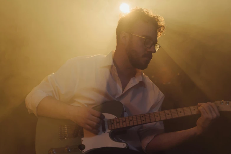 a man in a white shirt playing a guitar, by Matt Cavotta, happening, rhys lee, holding an electric guitar, slight haze, promo image