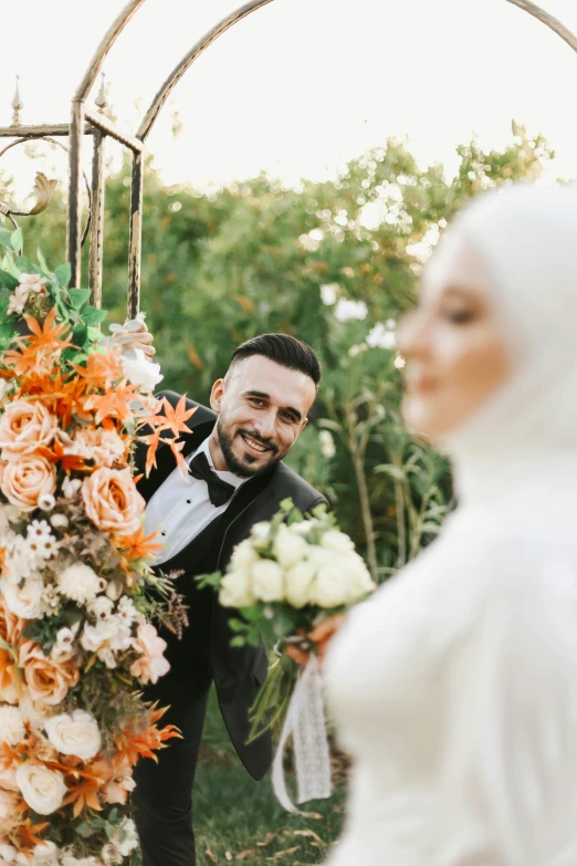 a man standing next to a women near a flower covered structure