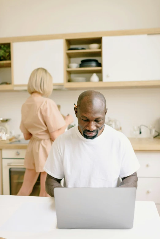 a man sitting at a table in front of a laptop computer, pexels contest winner, renaissance, in the kitchen, emmanuel shiru, man and woman, white hue