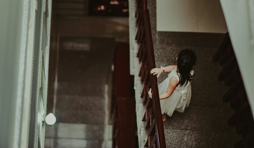 a little girl that is standing on some stairs, inspired by Elsa Bleda, pexels contest winner, happening, asian girl, many floors, spying, wearing white dress