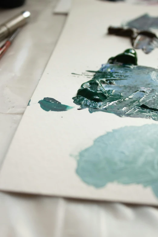 a close up of a piece of art on a table, inspired by Hu Zao, unsplash, process art, teal palette.”, on white paper, palette knife, teal color graded