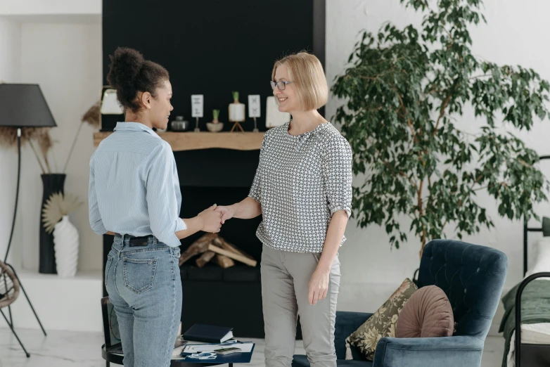 two women shaking hands in a living room, pexels contest winner, wearing business casual dress, without duplicate image, thumbnail, background image