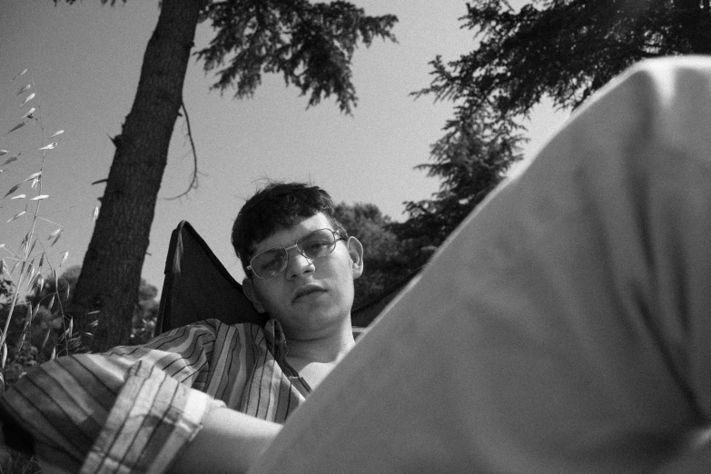 a black and white photo of a man laying in a chair, by Jan Rustem, teenage boy, picnic, brandon sanderson, 33mm photograph