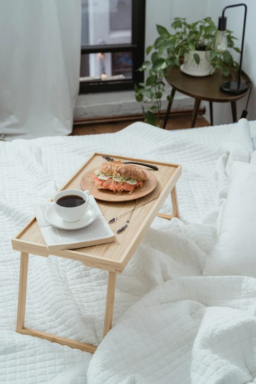 tray with food and coffee on bed next to window