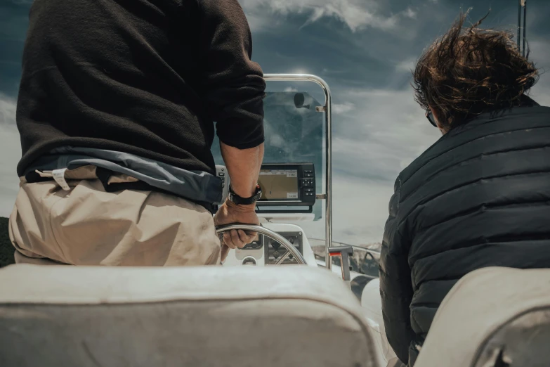 a couple of men sitting on top of a boat, close up to the screen, driving, top down photo, back towards camera