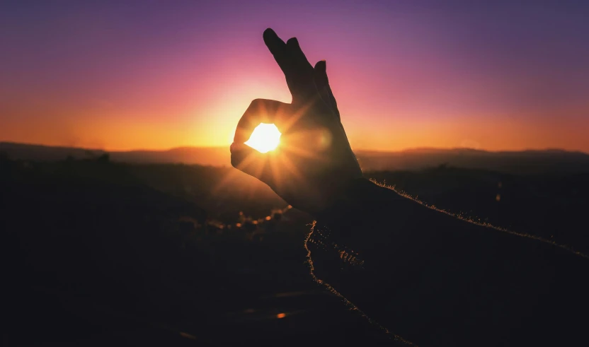 a hand making a peace sign with the sun setting in the background, pexels contest winner, during an eclipse, instagram post, magic light, purple sun