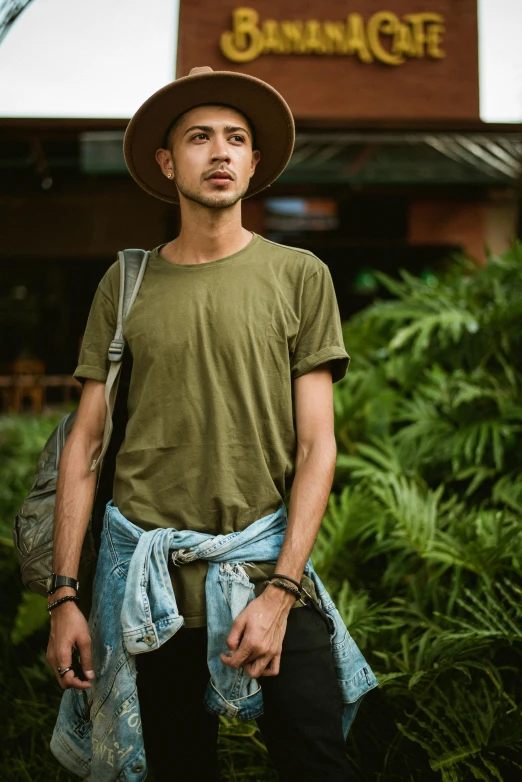 a man in a hat poses in front of a building