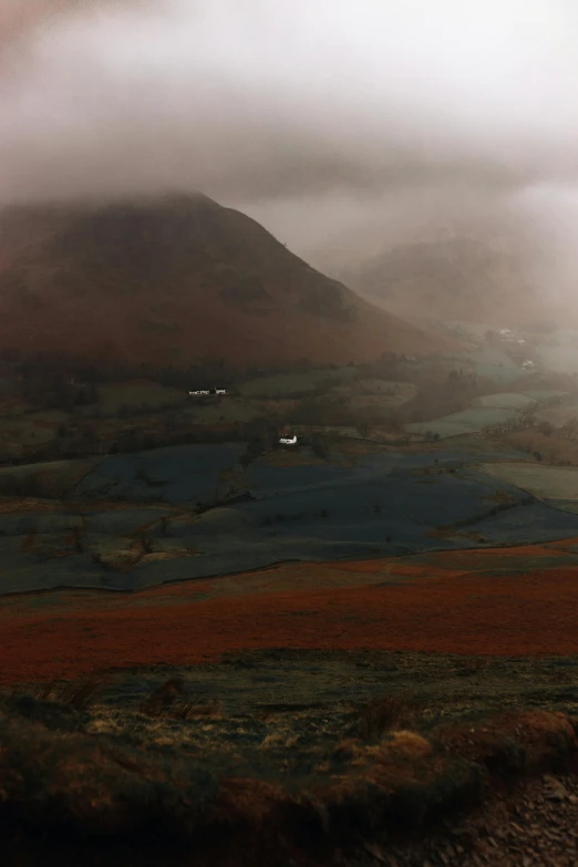 an aerial view of a valley and mountains on a foggy day