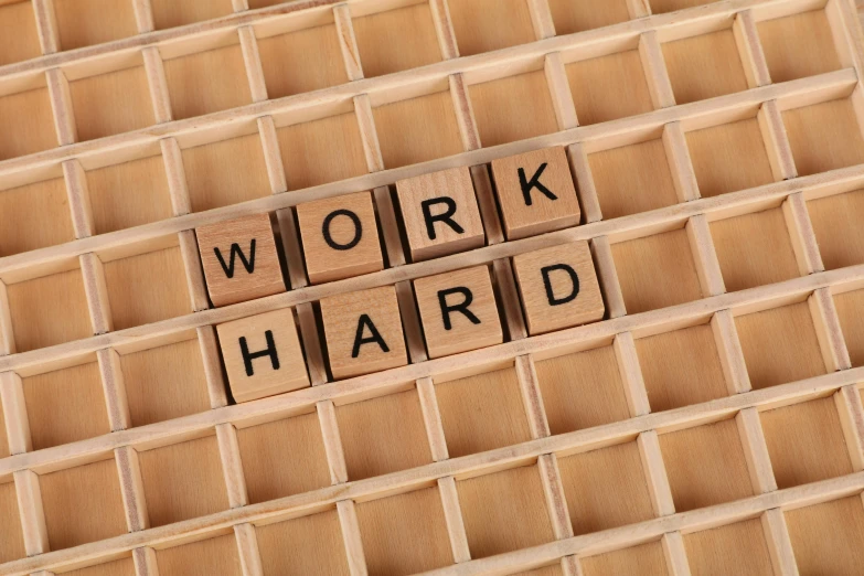 a wooden block with the word work hard written on it, an album cover, inspired by Paul Harvey, shutterstock, grid, 3 2 x 3 2, board games, sweat and labour