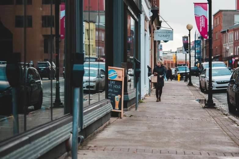 a person walking down a sidewalk in front of a store, by Carey Morris, pexels contest winner, minneapolis, commercial banner, old town, ayne haag