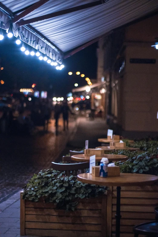 a couple of wooden tables sitting on top of a sidewalk, by Niko Henrichon, trending on unsplash, renaissance, night time footage, market stalls, seen from outside, looking left