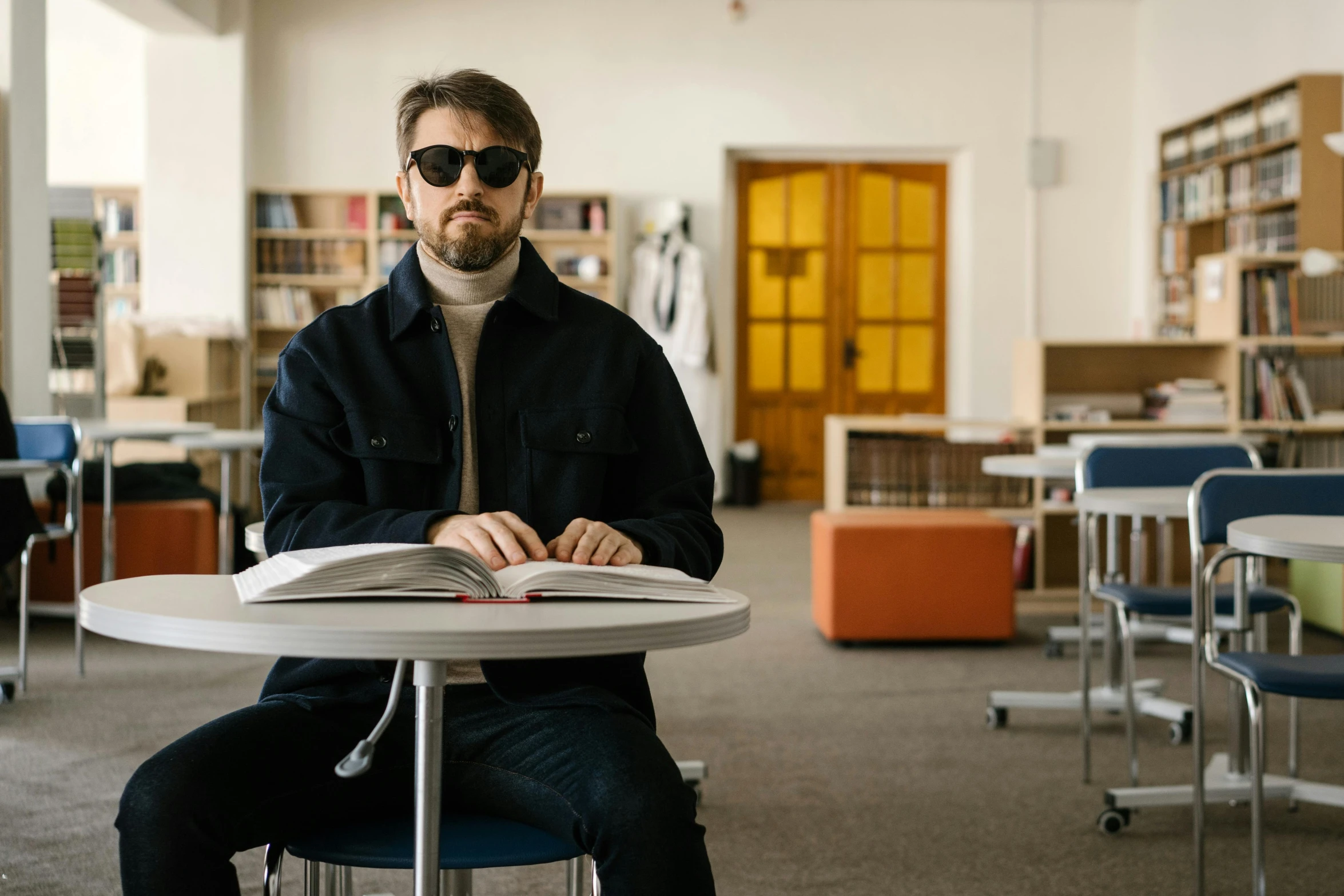 a man sitting at a table reading a book, trending on unsplash, hyperrealism, in a school classroom, wearing shades, charlie day, sitting on a chair