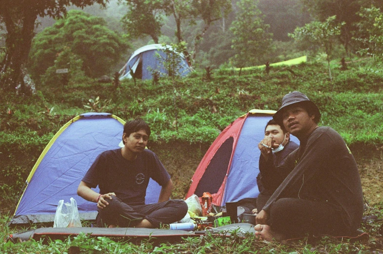 a group of people sitting on top of a lush green field, a picture, unsplash, sumatraism, he is at camp, avatar image