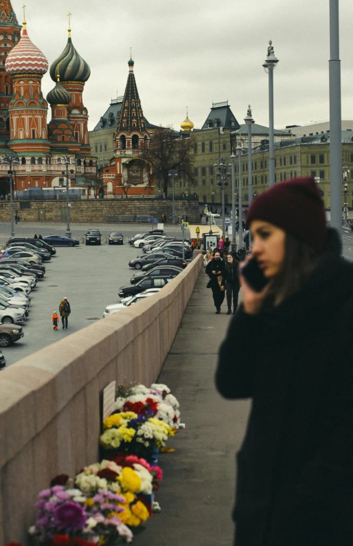 a woman standing on a bridge talking on a cell phone, a picture, inspired by Vasily Surikov, pexels, socialist realism, flowers in foreground, red square, walk in a funeral procession, square