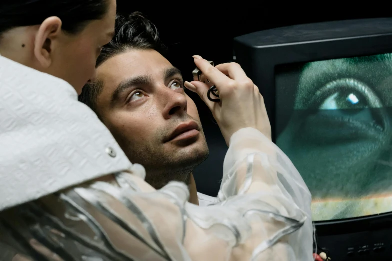 a man holding soing in his right hand, touching the monitor with an evil eye