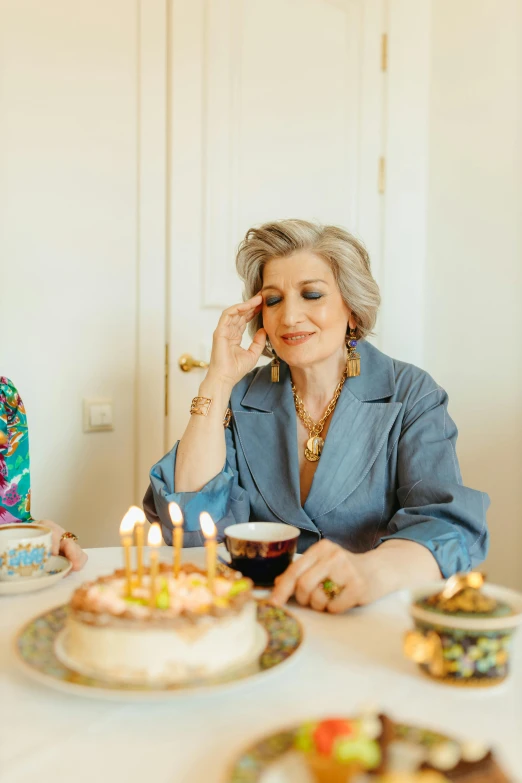 two women sitting at a table with a cake in front of them, an album cover, by Anita Malfatti, pexels, gray haired, birthday party, pensive expression, nadezhda tikhomirova