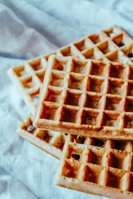 three waffles are laid on a white cloth