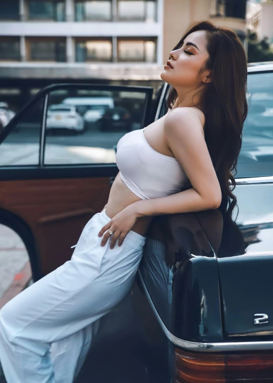 a woman in white pants leaning on the back of a black car