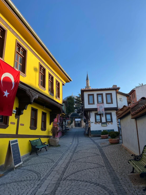 a yellow building with a turkish flag on it, inspired by Niyazi Selimoglu, pexels contest winner, pilgrim village setting, square, today\'s featured photograph 4k, cobblestone streets