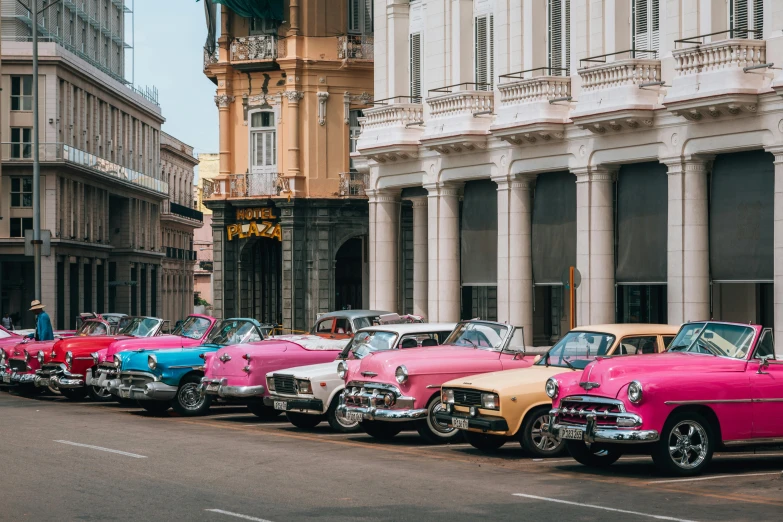 several classic cars line up for auction in a street