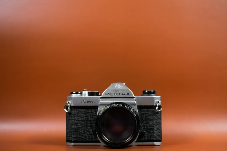 a camera sitting on top of a table, pexels contest winner, photorealism, 1980's, full front view, modern minimalist f 2 0 clean, in front of an orange background