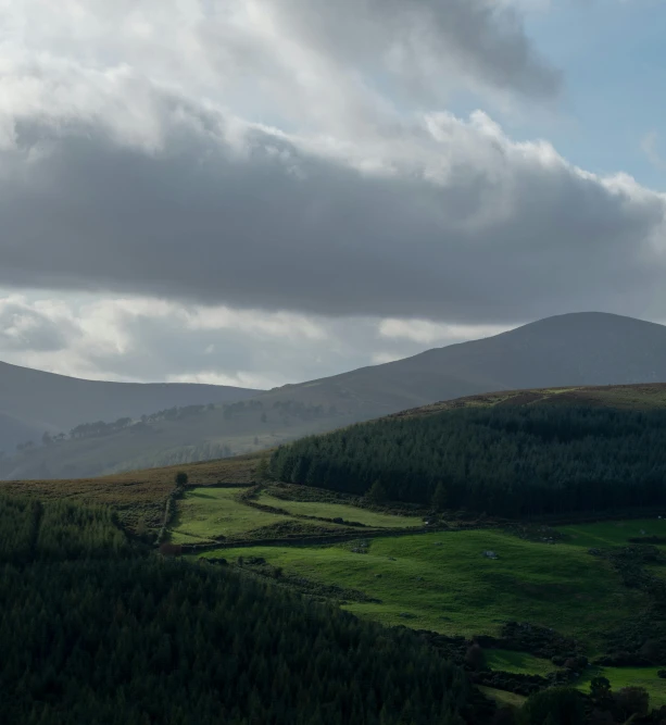 a hill and trees under some cloudy skies