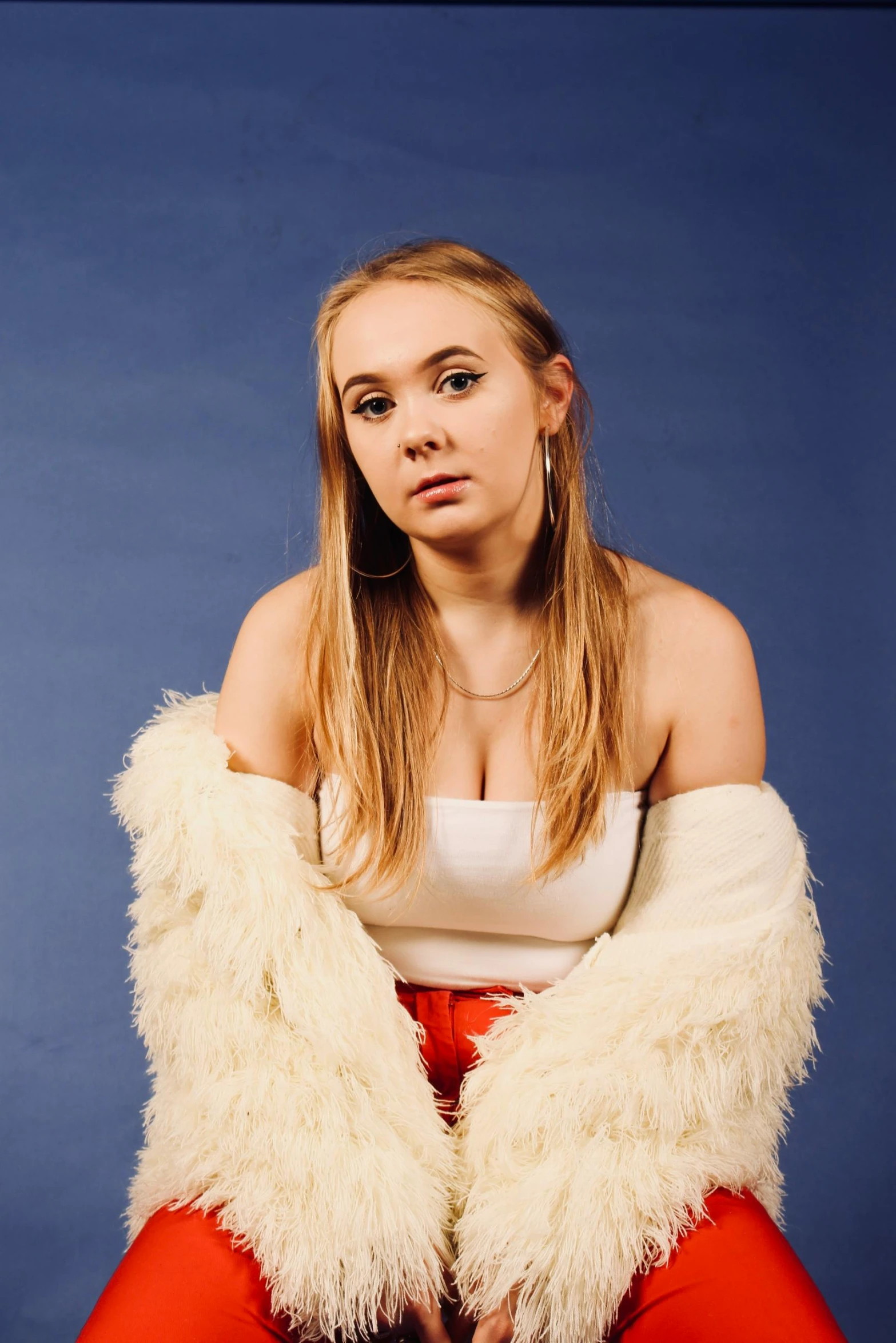 a woman in a white top and red pants, an album cover, inspired by Louisa Matthíasdóttir, unsplash, portrait of annasophia robb, studio photo portrait, smug look, devon cady-lee