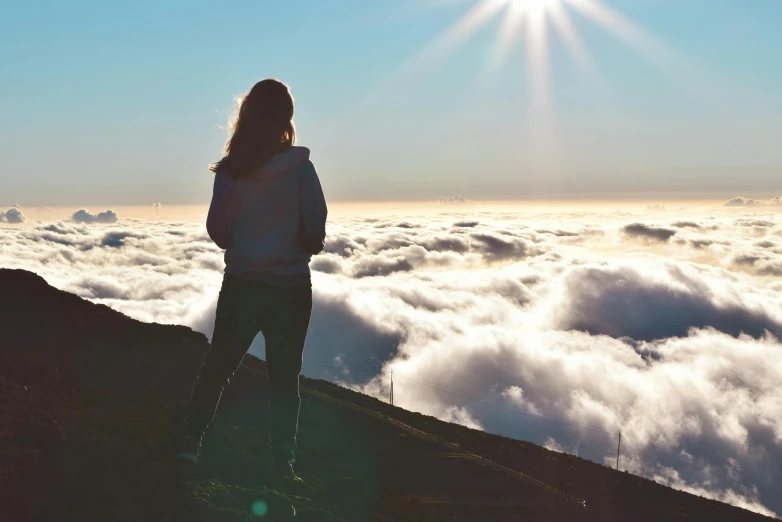 a woman standing on top of a mountain above the clouds, afternoon sun, avatar image, trending photo