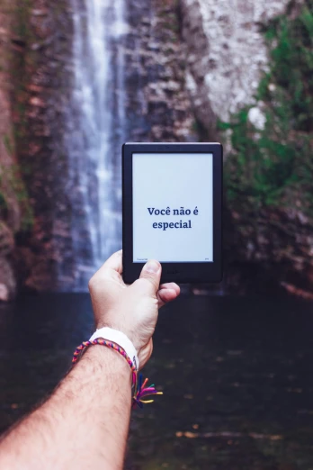 a hand is holding an empty small box in front of a waterfall