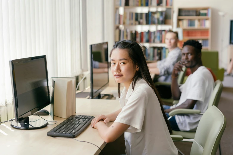 a woman sitting at a desk in front of a computer, by Jang Seung-eop, trending on pexels, school class, zeen chin and farel dalrymple, in a library, lachlan bailey