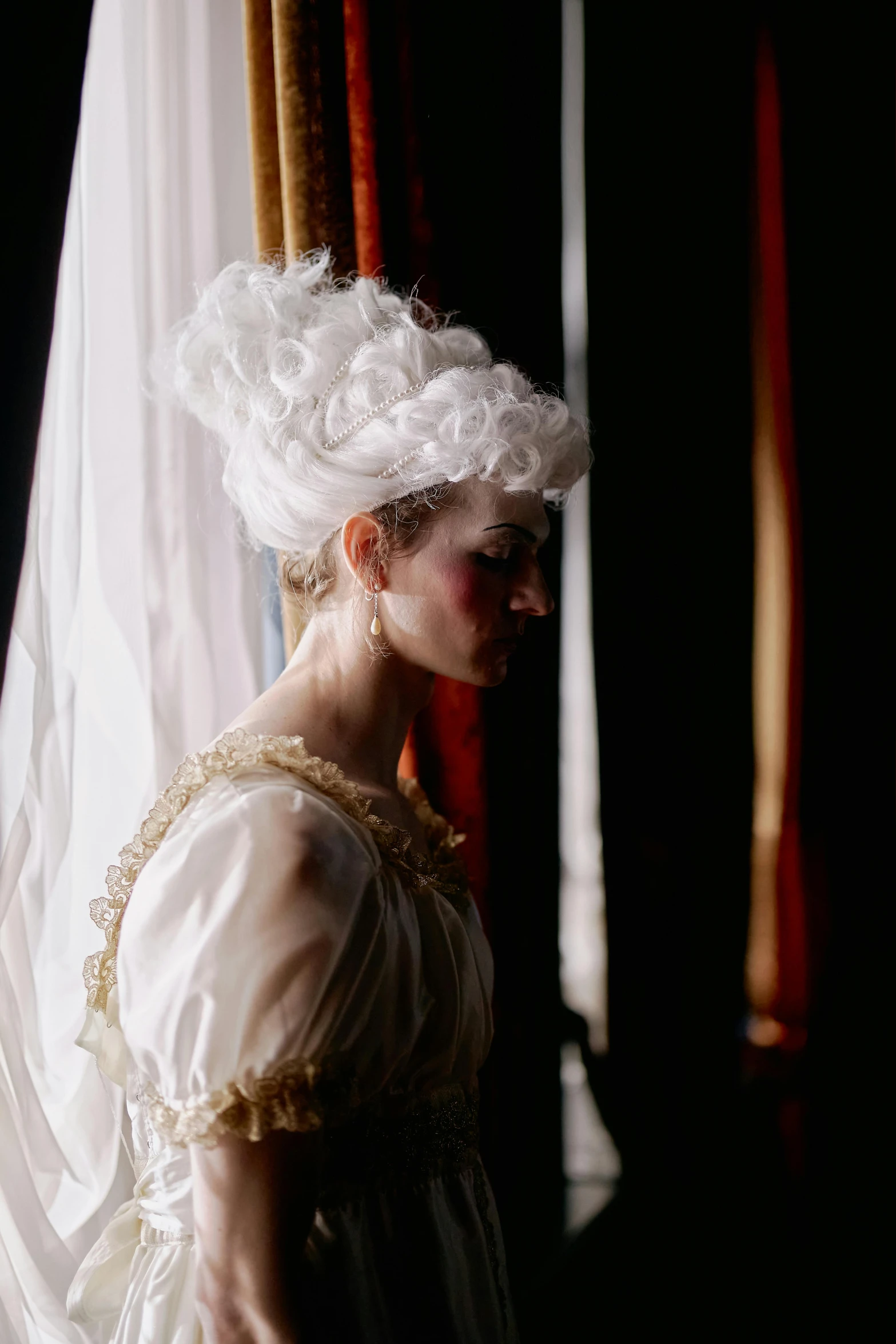 a woman standing by a curtain in a fancy dress