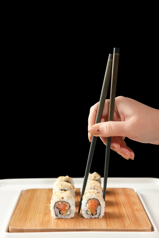 a person holding chopsticks over a plate of sushi, wooden magic wand, 2019 trending photo, sharp detail, square